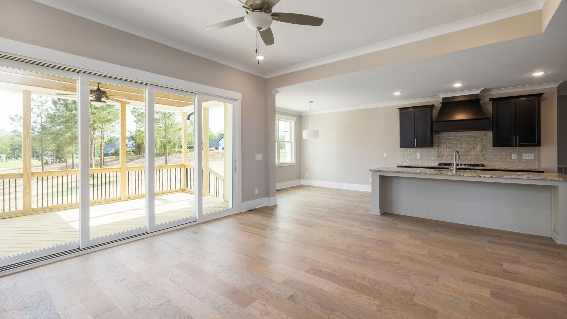 Modern open-concept kitchen and living room with hardwood floors and sliding glass doors to deck