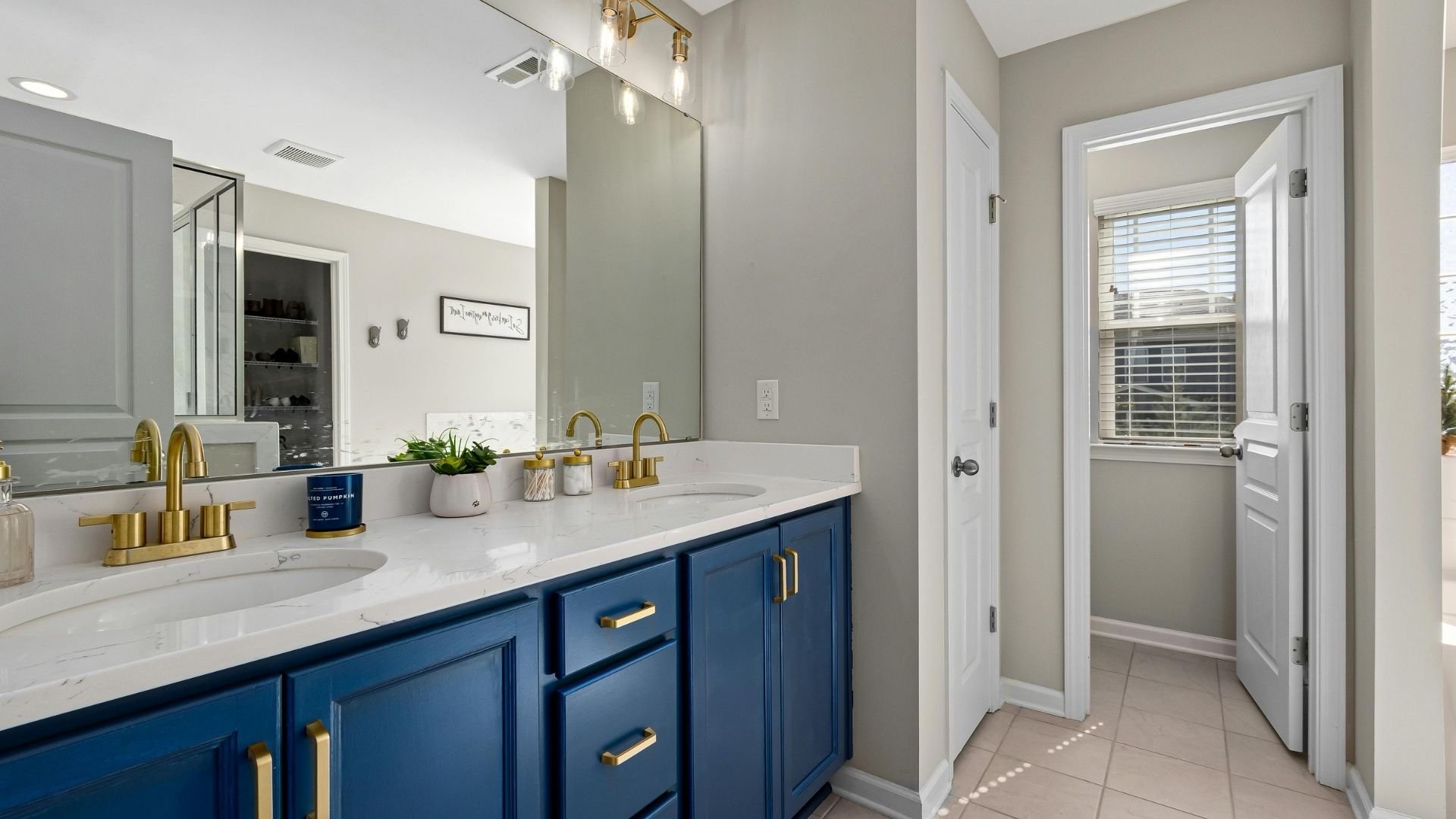 Modern bathroom with navy vanity, white marble countertop, and brass fixtures